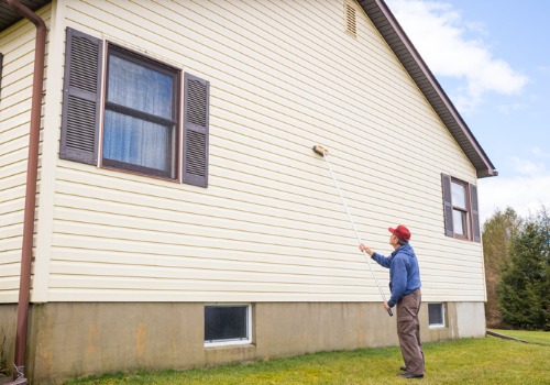 A man reaching high up with a brush, performing Siding Cleaning in Morton IL