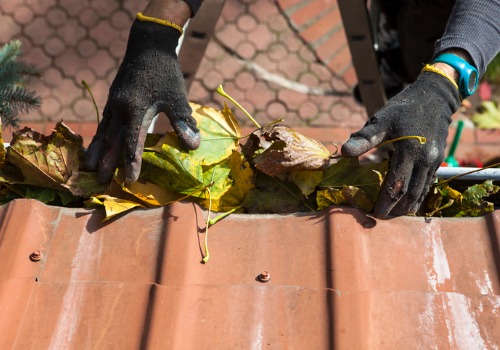 Man pulling leaves out of gutters during Gutter Cleaning Washington IL