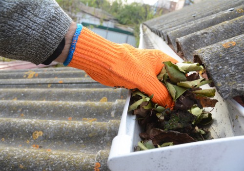 Person pulling leaves out of gutters during Gutter Cleaning in Dunlap IL