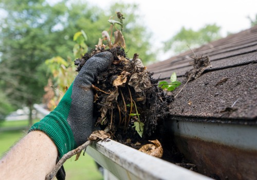 A team member of Flush the Guts, which offers the Best Gutter Cleaning in Peoria IL, cleans out debris from a gutter