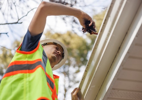 A team member of Flush the Guts, which offers the Best Gutter Cleaning in Peoria IL, cleans out a homeowner's gutters